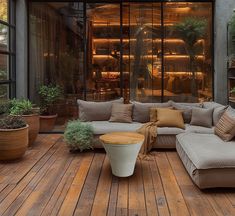 a large couch sitting on top of a wooden floor next to potted planters