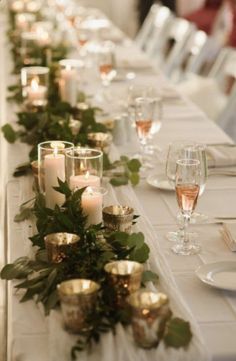 a long table with candles and greenery on it