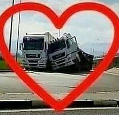 two trucks in the middle of a road with a red heart shaped frame over them