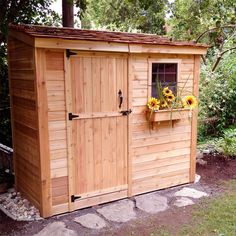 a wooden shed with flowers in the window