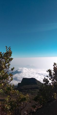 the view from top of a mountain with clouds below