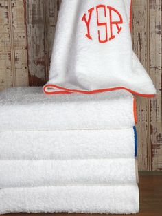 towels stacked on top of each other in front of a wooden wall with the monogrammed initials