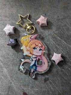 an anime character keychain laying on top of a table next to star shaped objects