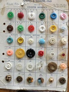 a bunch of different colored buttons sitting on top of a white piece of paper next to each other