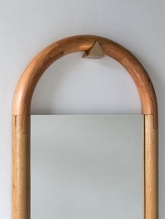 a mirror hanging on the wall next to a wooden frame with an arch shaped mirror above it