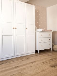 a baby's room with two white wardrobes and a crib in the corner