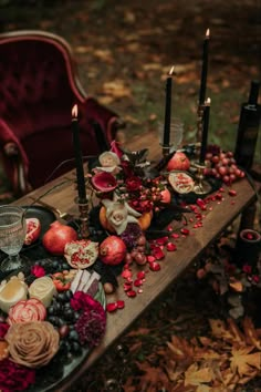 a wooden table topped with lots of candles next to a red chair and some flowers