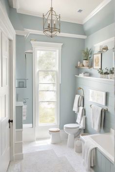 a bathroom with blue walls and white fixtures, including a chandelier above the toilet