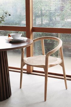 a wooden chair sitting next to a table with a bowl and cup on top of it