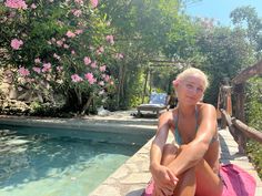 a woman sitting on the edge of a swimming pool