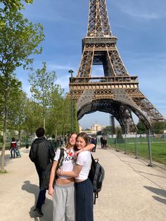 two girls standing in front of the eiffel tower with their arms around each other