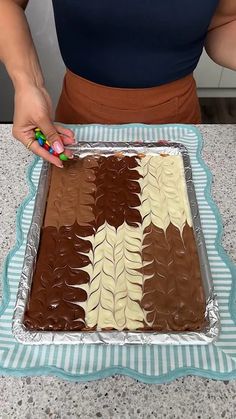 a woman is decorating a chocolate cake with icing