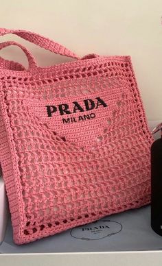 a pink crocheted bag with the word prada on it's side