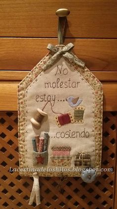 a cross stitched wall hanging on the side of a wooden cabinet with words written in it