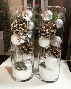 two clear vases filled with snow and pine cones