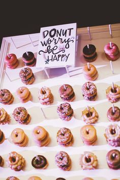 there are many donuts on the table and one has a sign that says donut worry be happy