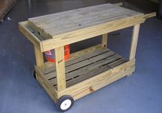 a cart made out of pallet wood with wheels and an orange bucket on top