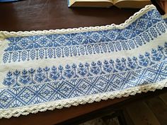 a blue and white table cloth on top of a wooden table next to an open book