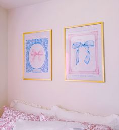 two framed pictures hang on the wall above a bed with pink and white sheets,