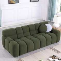 a green couch sitting on top of a hard wood floor next to a white wall