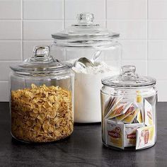 three glass jars filled with cereal sitting on top of a counter next to each other