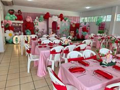 a room filled with lots of tables covered in pink and white cloths next to balloons