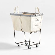 a white shopping cart with two canvas bags on the front and one is attached to it