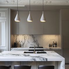 a kitchen with marble counter tops and stools in front of an island that has three pendant lights hanging from the ceiling