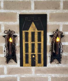 two wall sconces with candles on them are hanging from the side of a brick wall