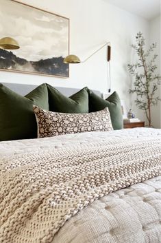 a bed with green pillows and blankets on it