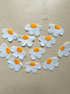 felt flowers are arranged in the shape of hearts on a wooden surface with twine