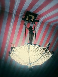 a man standing on top of a boat in the middle of a red and white striped room