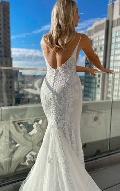 a woman in a white wedding dress standing on a balcony looking out at the city