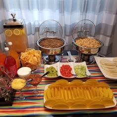 an assortment of food is displayed on a table with plates and bowls in front of it