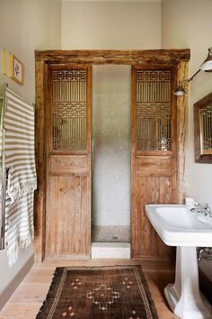 a bathroom with wooden doors and a rug on the floor