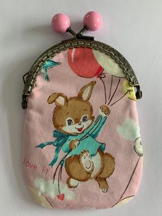 a small pink purse with an image of a teddy bear holding a balloon