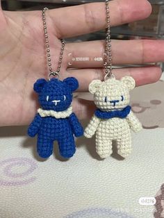 two small crocheted teddy bears are being held by someone's hand