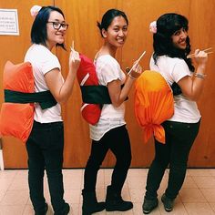 three young women standing next to each other with chopsticks in their hands and one holding an orange bag