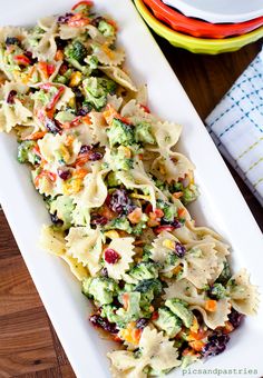 pasta salad with broccoli and cranberries in a white dish on a wooden table