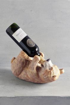 a bottle of wine sitting on top of a wooden animal shaped object with a corkscrew