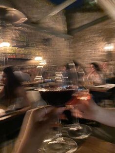 blurry image of people sitting at a table with wine glasses