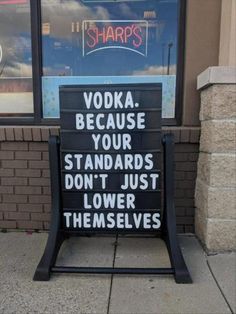 a sign that reads vodka because your standards don't just lower themselvess on the sidewalk