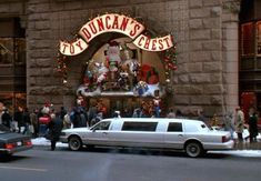 a white limousine parked in front of a building with christmas decorations on it's side