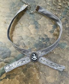 This is my version of the family crest choker as seen worn by the amber eyed vampire family. The crest is set behind glass into an antiqued silver bezel. Its attached to a 14 inch choker with an adjustable clasp. The choker is made of cotton and lace, carefully stitched together to give it a unique antique shabby chic feel. This makes an excellent gift for a loved one or yourself. Silver Vampire Choker For Halloween, Silver Vampire Style Choker Necklace, Vintage Silver Beaded Choker, Silver Vampire Costume Jewelry, Vintage Silver Choker For Gift, Vintage Silver Choker As Gift, Silver Vampire Style Costume Jewelry, Victorian Silver Costume Jewelry, Silver Choker For Halloween Gift