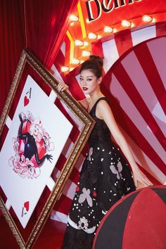 a woman in a black dress holding up a picture