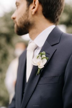 a man in a suit and tie with a flower on his lapel buttonhole