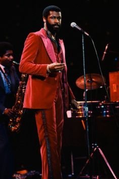 a man in a red suit is standing next to a microphone and saxophone on stage