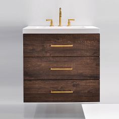 a white sink sitting next to a wooden cabinet with two gold faucets on it