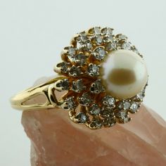 14K Yellow gold Large White Pearl and 1.2ct estimate Diamond Halo Ring, 8mm pearl center, 3 rows of tiered diamonds G color SI1 clarity, .75 inch across, sits 5/8 inch off finger, open work half shank, split shank, Ring size 6, Circa 1970, 10.5 grams Stock # BB258R11 This listing contains photographs of the actual item you will receive. Our items are in excellent condition with little or no signs of wear and many are one of a kind pre-owned estate finds. Please look closely at the pictures in th Gold Cluster Pearl Ring For Formal Occasions, Gemstone Rings Vintage, Diamond Pendants Designs, Split Shank Ring, Diamond Halo Ring, Split Shank, Bling Rings, Halo Diamond Ring, Fine Jewelry Designers