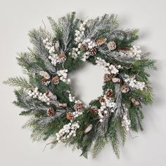 a christmas wreath with pine cones and white berries